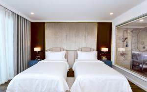 two beds in a hotel room with white sheets at Centara Hotel & Residences Van Don in Cái Rồng