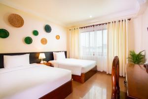 a hotel room with two beds and a window at Apsor Villa in Phumĭ Réach Born (2)