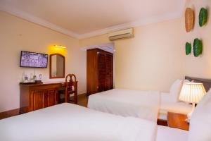 a bedroom with two beds and a desk and a mirror at Apsor Villa in Phumĭ Réach Born (2)