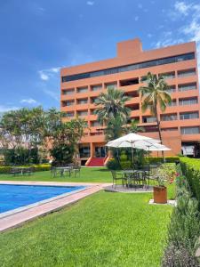 a hotel with tables and umbrellas in front of a building at Hotel de Cuautla in Cuautla Morelos +58 photos