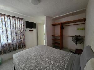 a bedroom with a bed and a window with a fan at Casa Golden in Barrio Nuevo