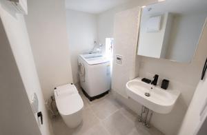 a white bathroom with a toilet and a sink at The Aoca Tokyo Kaminoge in Tokyo