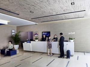 a group of people standing at a counter in a lobby at Shenzhen Novotel Watergate in Shenzhen