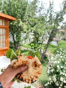 a person holding a tortilla with a lettuce and tomato at Thangkop House in Leh