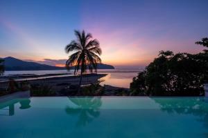 a swimming pool with a palm tree and a sunset at Hortensia Luxury Beach Villa in Chaloklum