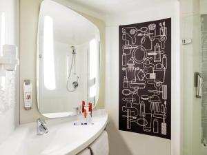 a bathroom with a mirror and a white sink at Ibis Den Haag City Center in The Hague