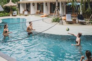 a group of people playing volleyball in a pool at Roomates Beach Hostel Canggu by Ini Vie Hospitality in Canggu