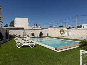 a swimming pool with lounge chairs on the grass at Chalet Escapada in Seville