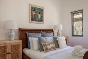 a bedroom with a bed with a painting on the wall at Lockn Heart Homestead in Quindalup
