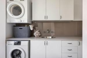 a white kitchen with a washing machine and a sink at Lockn Heart Homestead in Quindalup