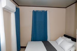 a small bedroom with a bed with blue curtains at Casa Lumina in Tinuric