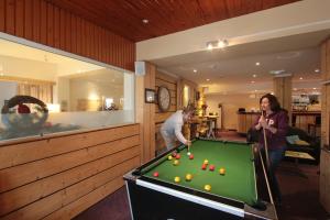 a man and a woman playing pool in a room at Le Christiania in Saint-Lary-Soulan