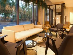 a living room with a couch and tables and chairs at Novotel Suites Berlin City Potsdamer Platz in Berlin