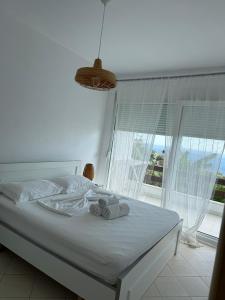 a bedroom with a bed with white sheets and a window at Olives Residence in Dhërmi +137 photos