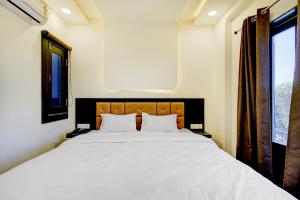 a bedroom with a large white bed with two pillows at Hotel O Bonsai in Bhopal