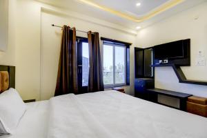 a bedroom with a large white bed and a window at Hotel O Bonsai in Bhopal