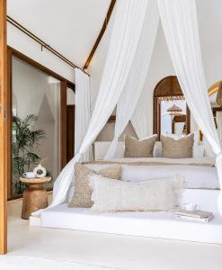 a bedroom with two beds with white drapes at Belajar Bali Boutique Hotel and Retreat in Canggu
