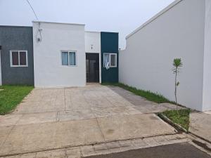 a white building with a driveway in front of it at Hermosa casa cerca de todo in Sitio del Niño