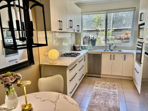 a kitchen with white cabinets and a table and a sink at Beautiful Brighton in Melbourne