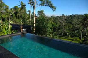 a swimming pool in a resort with trees in the background at The Ruler Bali in Penginyahan