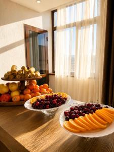 a table with plates of fruits and vegetables on it at Firdavsi Hotel in Dushanbe