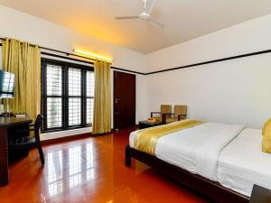 a bedroom with a bed and a desk and windows at Mannath Ayur Island Resort in Murinjupuzha