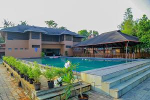 a swimming pool with plants and a building at Mannath Ayur Island Resort in Murinjupuzha