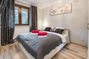 Un dormitorio con una cama con almohadas rojas. en Apartamenty Szkolna Zakopane, en Zakopane