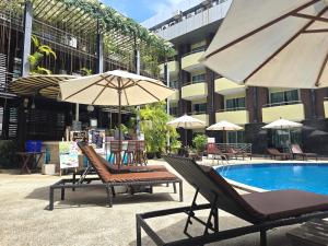 a pool with chairs and umbrellas next to a building at Baron Beach Hotel in Pattaya