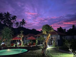 a villa with a swimming pool at night at Aqua Dive resort Amed in Amed