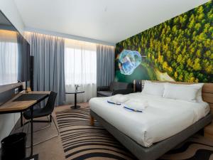 a hotel room with a large bed and a desk at Novotel Vilnius Centre in Vilnius