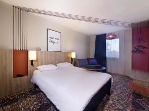 a hotel room with a large bed and a chair at ibis Styles Toulouse Lavaur in Lavaur +154 photos
