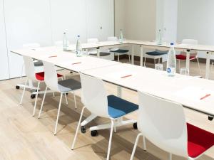 a long white table and chairs in a room at Ibis Elche in Elche