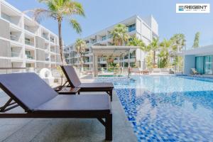 a swimming pool with a chaise lounge next to a building at The Regent Phuket Bangtao Beach in Bang Tao Beach