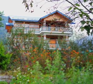 a house on a hill with flowers in front of it at Enroot Manali in Vashisht