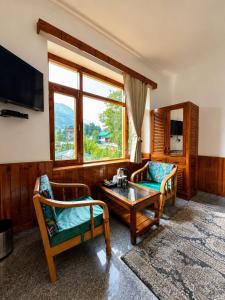 a living room with two chairs and a coffee table at Enroot Manali in Vashisht