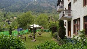a yard with chairs and an umbrella and a table at Hotel king palace in Pahalgām