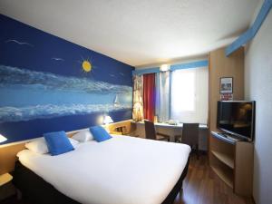 a hotel room with a large bed and a desk at ibis Fribourg in Fribourg