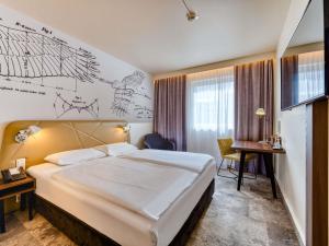 a hotel room with a large bed and a desk at Mercure Hotel Berlin City in Berlin