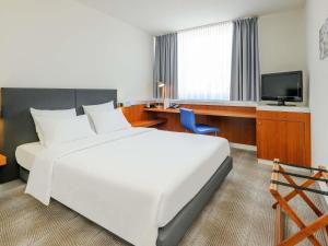 a hotel room with a large bed and a television at Novotel Erlangen in Erlangen +101 photos