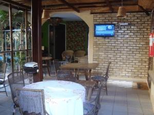 een patio met tafels en stoelen en een tv aan een bakstenen muur bij Pousada Alamanda in Natal