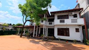 a white house with a tree in front of it at Iris Grand Hotel in Nittambuwa