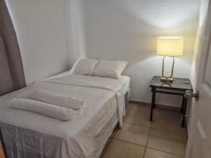 a small room with a bed and a table with a lamp at Hermosa casa con piscina in Sitio del Niño