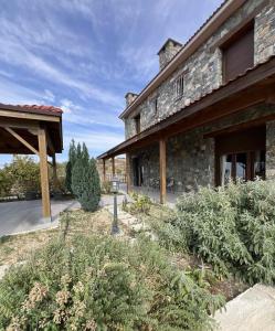 a stone building with a porch and some bushes at Kyperounta Heights - Breathtaking View in Kyperounda