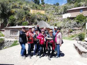 a group of people posing for a picture in front of a mountain at Lake HOME in Puno
