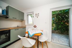 a kitchen with a table and white chairs at Apartment and rooms Jurišić in Korčula