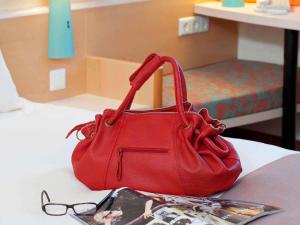 a red purse sitting on a bed next to a magazine at Ibis Madrid Alcorcon Tresaguas in Alcorcón +87 photos