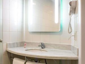 a bathroom with a sink and a phone on the wall at ibis Araçatuba in Araçatuba +83 photos