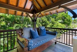 a porch with a bench with blue pillows on it at Monsoon Villa A - Central Balinese-style Pool Oasis in Port Douglas +36 photos