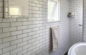a white tiled bathroom with a sink and a mirror at Gorgeous Home In Hundested With Wifi in Hundested
